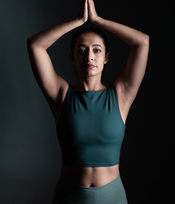 Woman in a calm yoga pose in a dark studio with coral light.